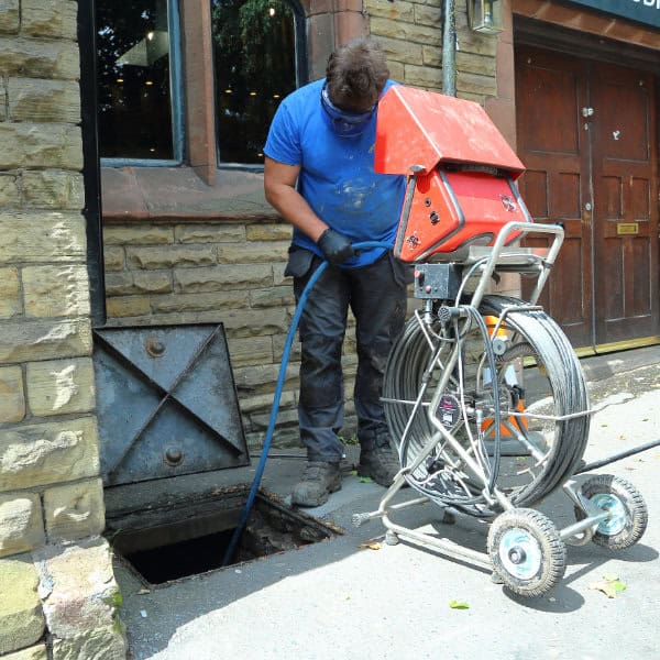 A drain cleaner working on a drain outside a bar