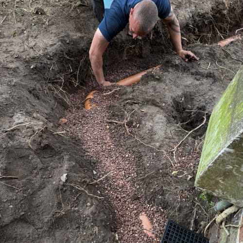 A drain engineer beginning to dig up the ground where a new drain installation will be laid