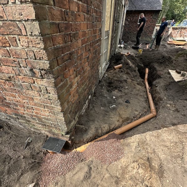 Two drain engineers undertaking a new drain installation in a back garden