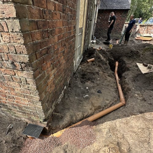 Two drain engineers completing a drain repair on a residential house drain