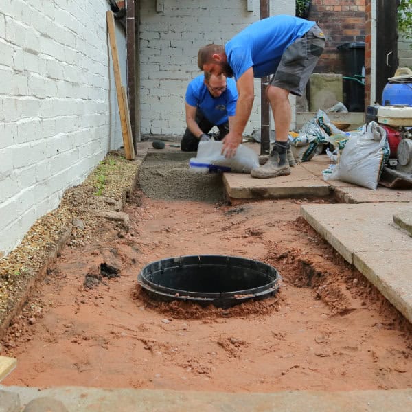 Two drain repair engineers relaying the ground after completing a drain repair